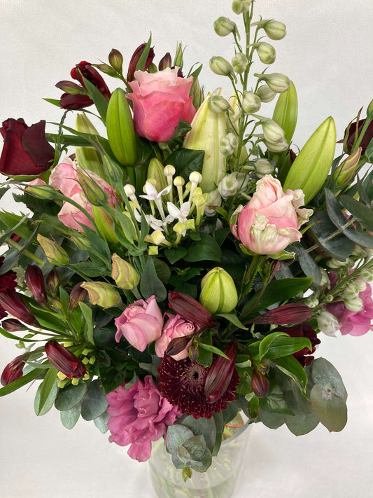 Angle from above looking down on a romantic bouquet consisting of roses, lillies, and other fresh blooms