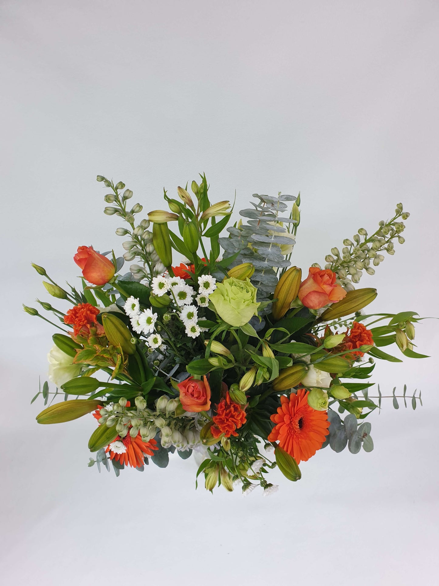An orange, white, and green bouquet from above.