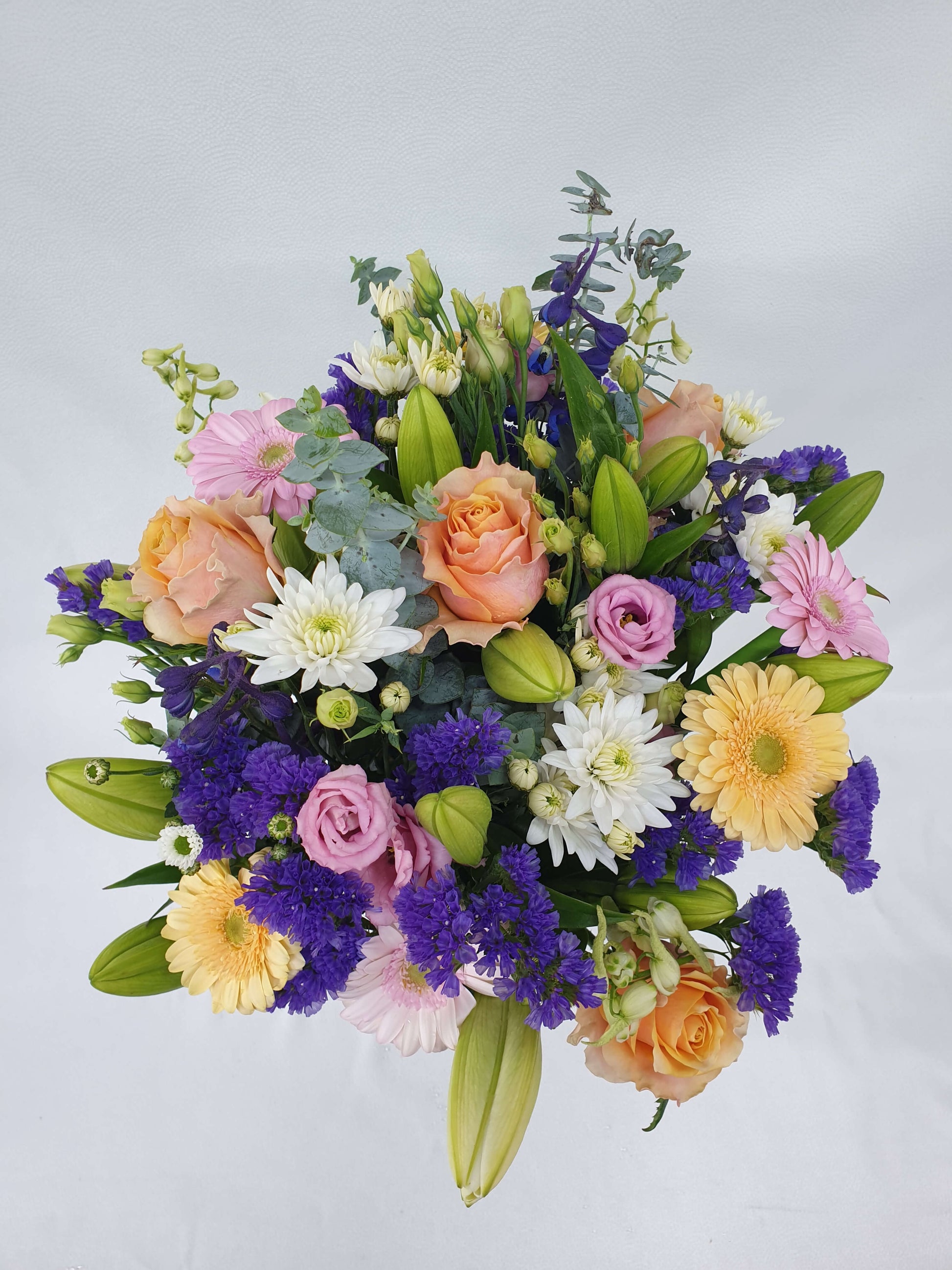 A colourful bouquet from above. Thee are pink, orange, purple, yellow, green, and white flowers.