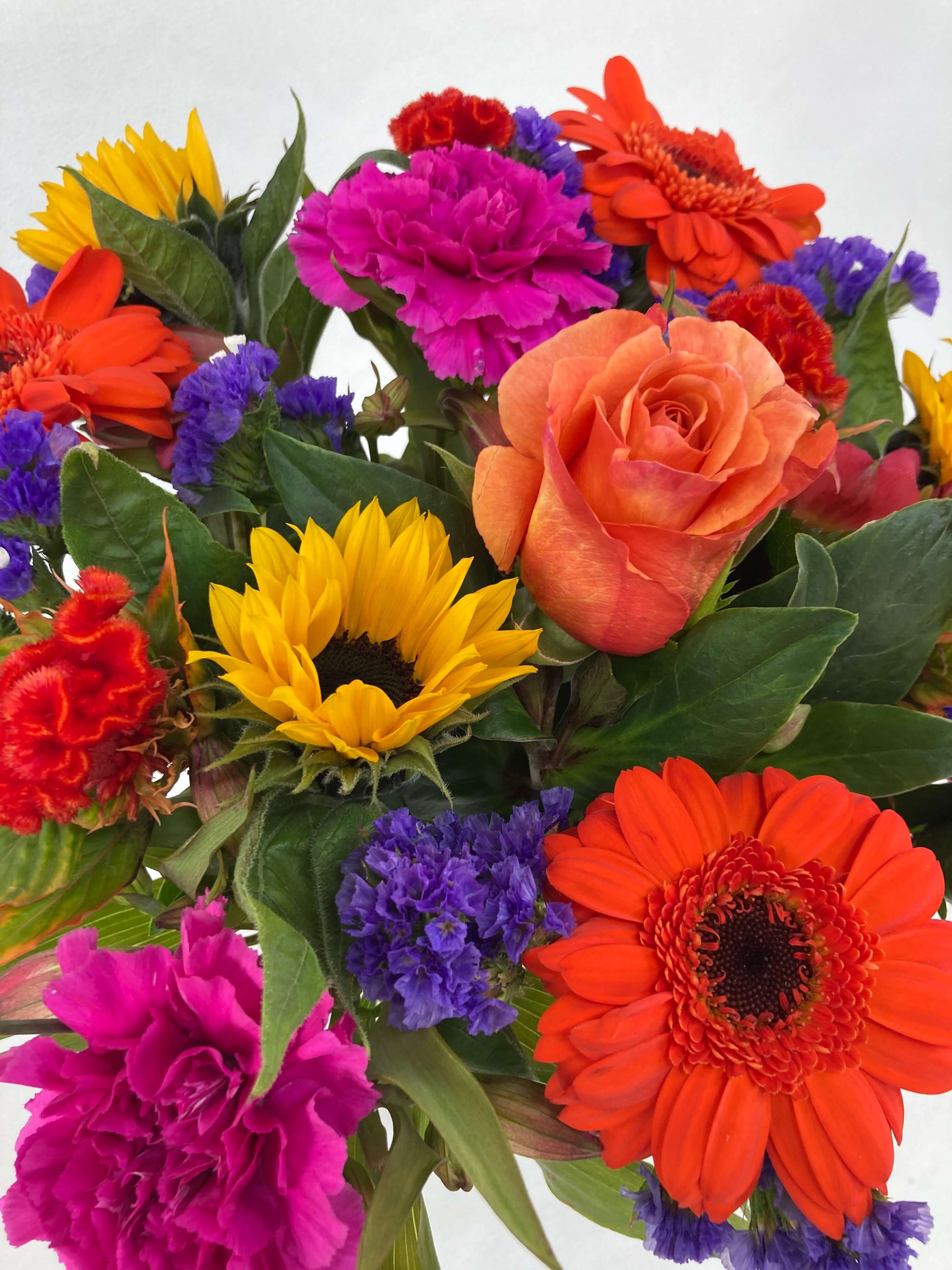 Bright posy consisting of orange, yellow, red, purple, and green flowers up close