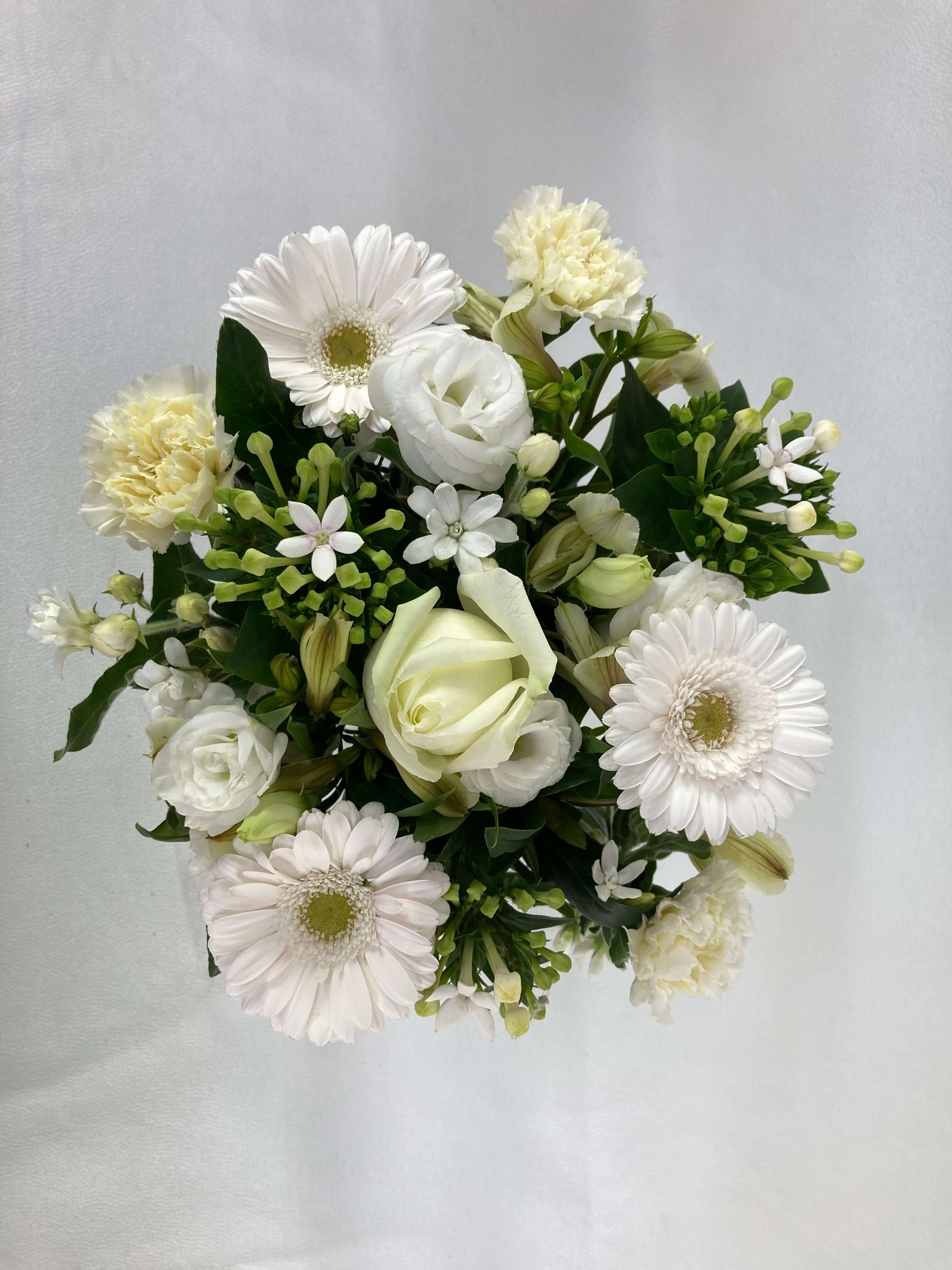 Top view looking over the short-stemmed posy flower arrangement of white and green blooms.